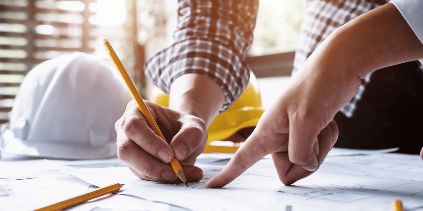 Two civil engineers pointing to a blueprint and making notes on it